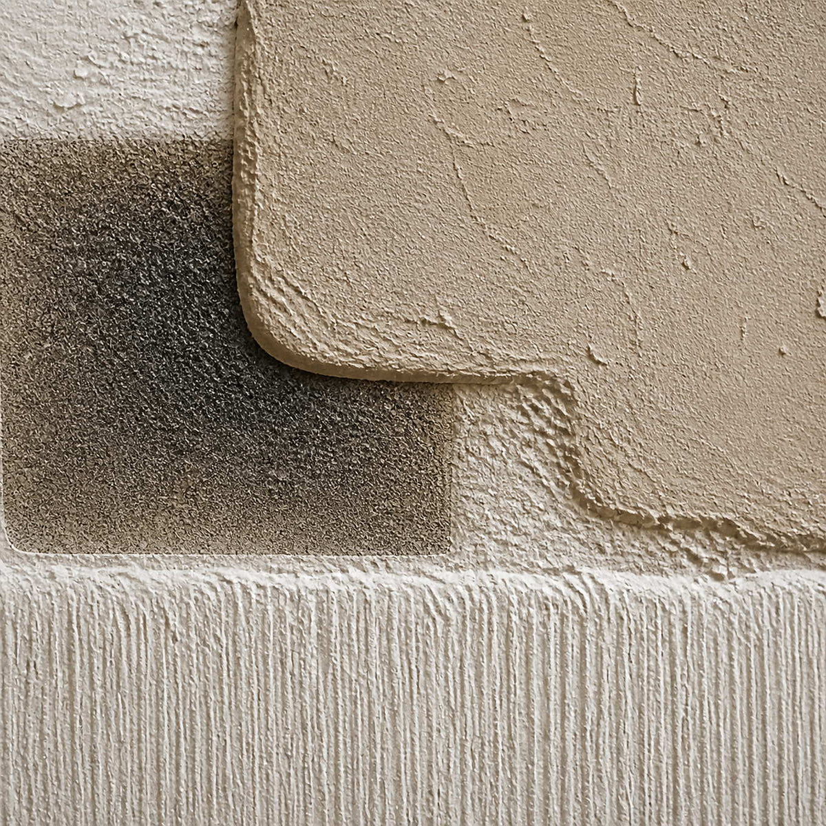 Close-up of beige, white, and charcoal layered plaster relief texture.
