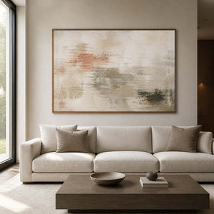 Neutral abstract wall art in a wood frame above a bright living room sofa.