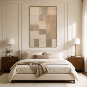 Wood framed cream and taupe abstract artwork above a softly layered bed.
