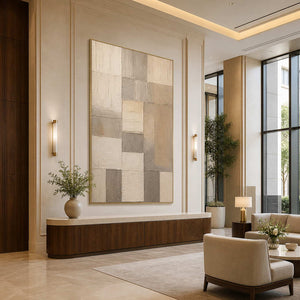 Gold framed neutral geometric artwork above a curved console in a hotel lobby.