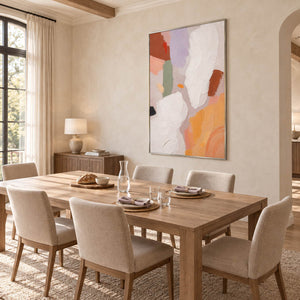 Abstract painting with ivory, lilac, sage, terracotta, and ochre forms in a silver frame in a dining room.