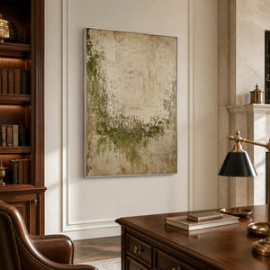 Silver framed green and beige textured painting beside bookshelves in a traditional study.