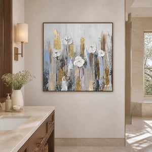Wood framed white floral artwork beside a pale stone bathroom vanity and sunlit window.
