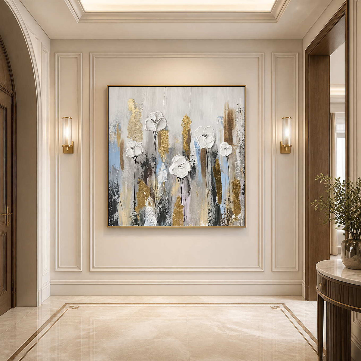 Gold framed white floral painting between warm wall sconces in a paneled cream hallway.