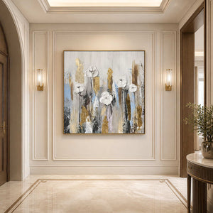 Gold framed white floral painting between warm wall sconces in a paneled cream hallway.