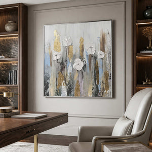 Silver framed white floral artwork beside a wooden desk and a cream office chair.