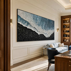 Black framed shoreline painting beside a wooden desk and pale blue study sofa.