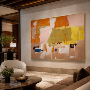 Gold framed colorful abstract artwork above upholstered seating in a softly lit hotel lounge.