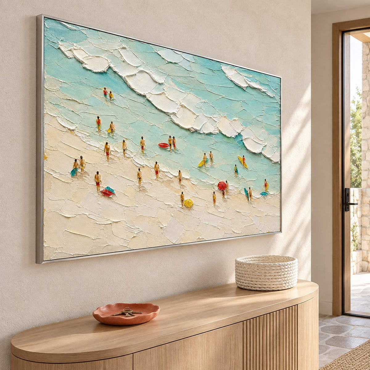 Textured beach painting with sea-glass waves and small beachgoers in a silver frame in an entryway.