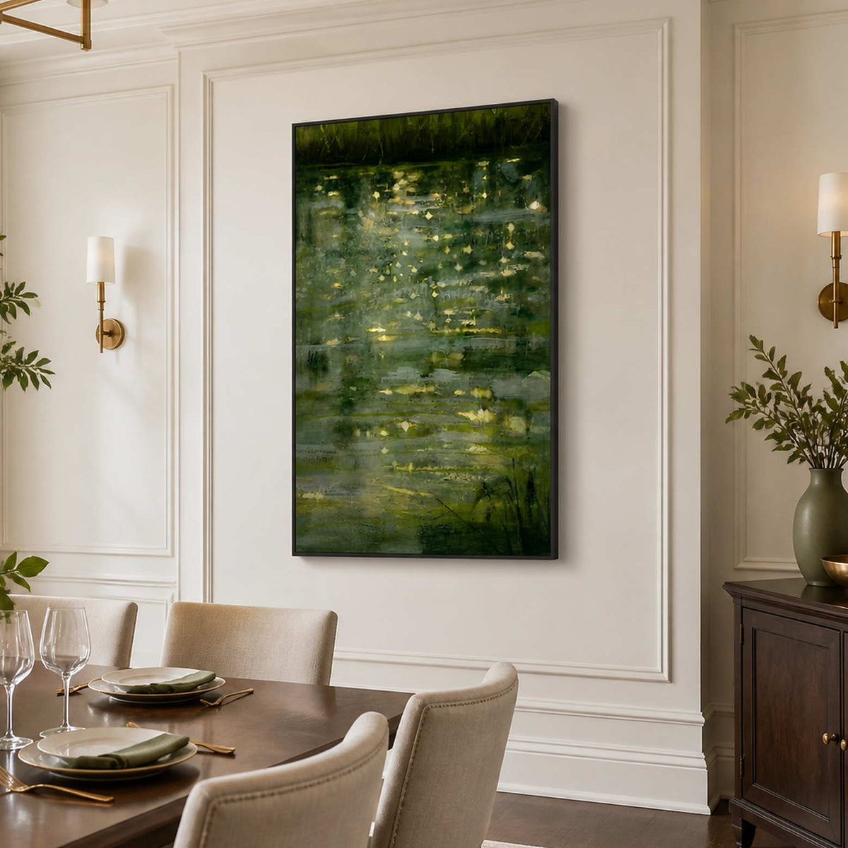 Black framed green water painting beside a dining table with cream upholstered chairs.