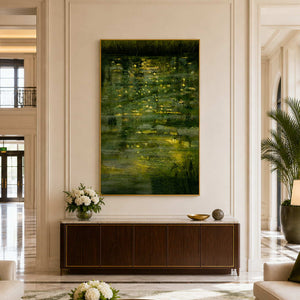 Gold framed waterside painting above a dark cabinet in a spacious hotel lobby.