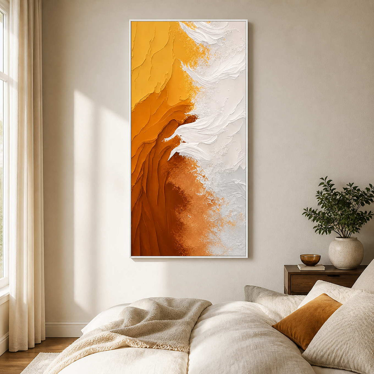 White framed amber and white textured artwork beside neutral bedding and an ochre cushion.