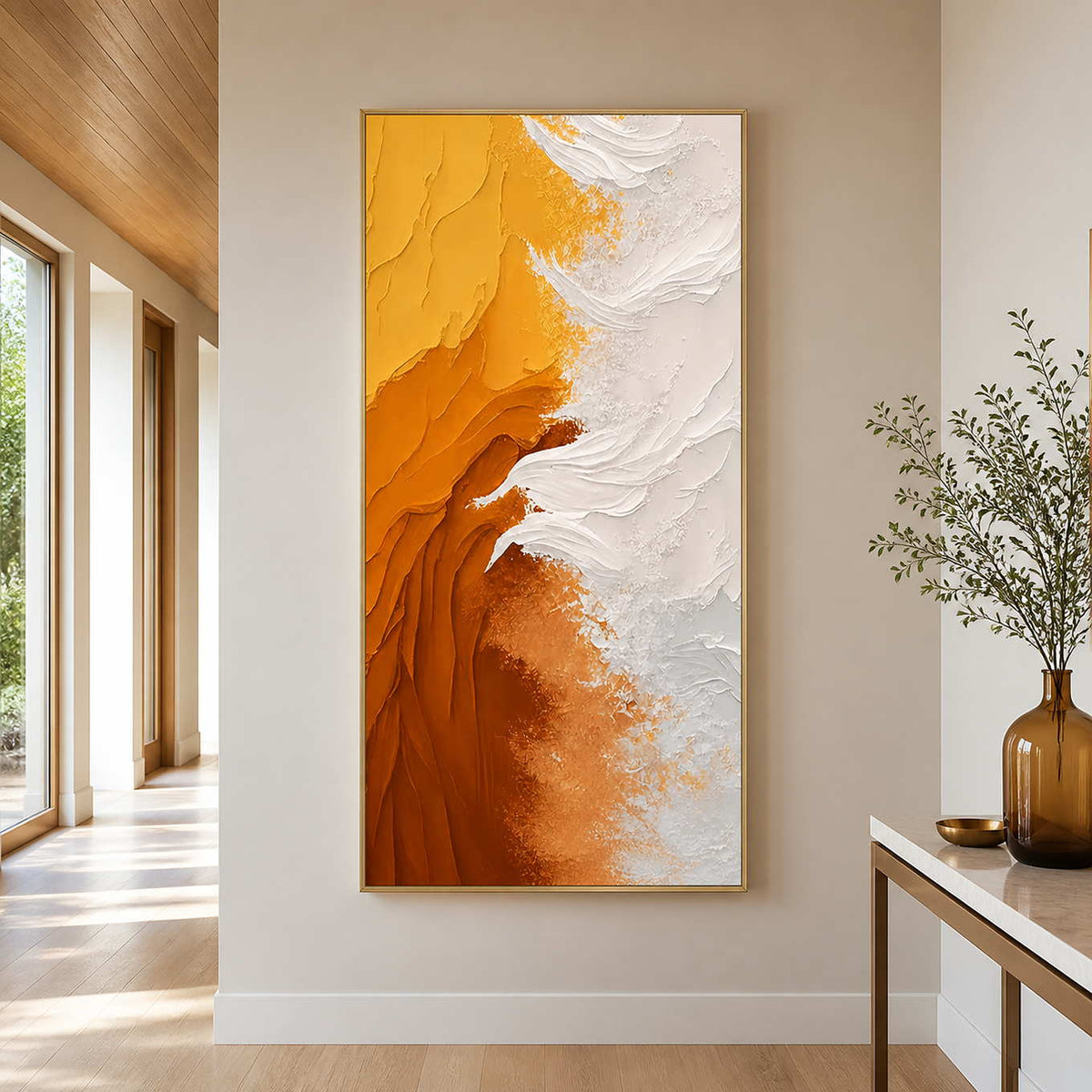 Gold framed amber and white textured artwork on a sunlit hallway wall.