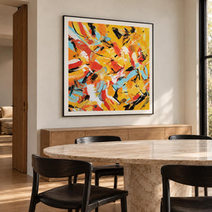 In a dining area beside the table, an artwork with a black frame shows interlocking yellow, orange, light blue, white and black abstract strokes.