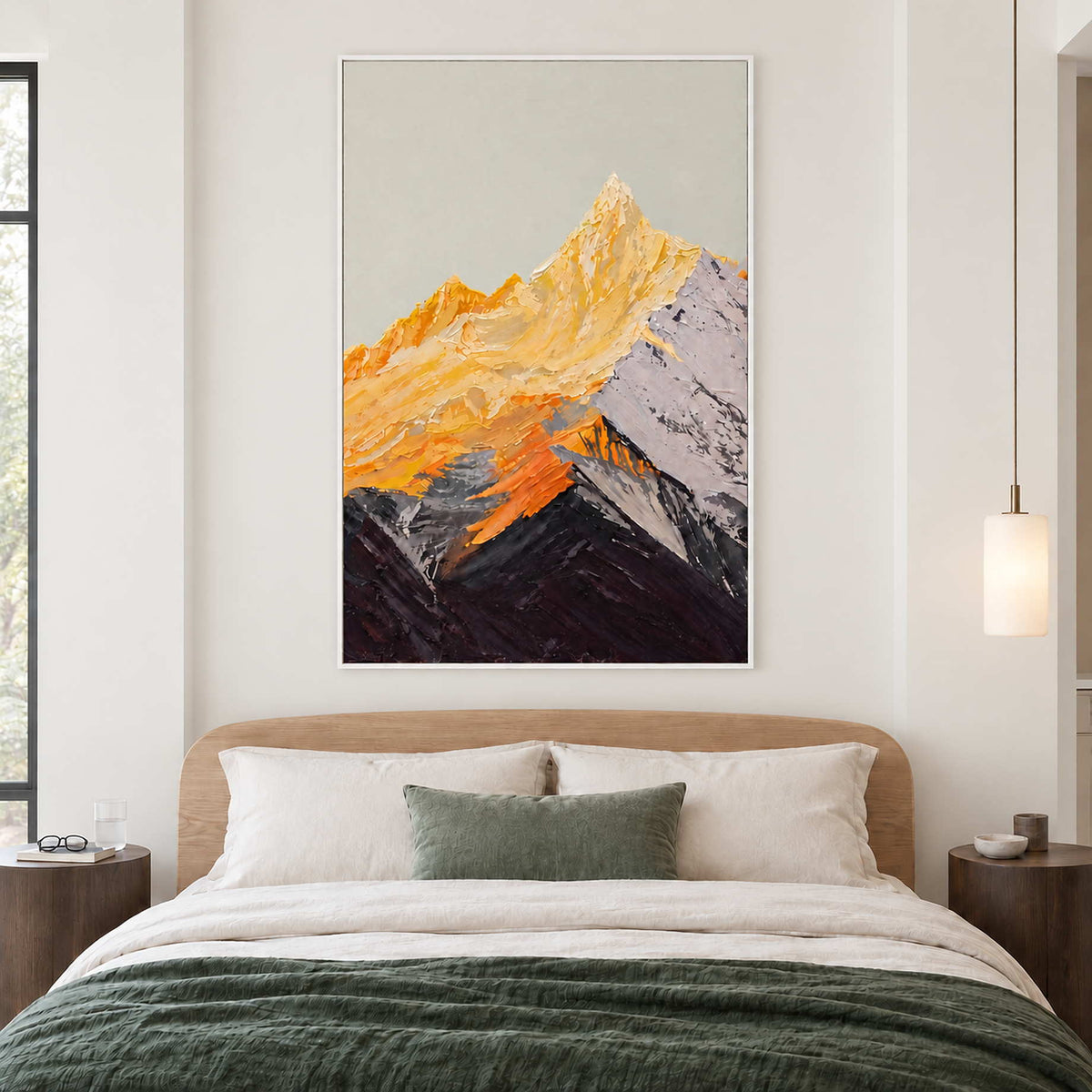 White-framed golden mountain artwork above a wooden bed with white pillows and a dark green cover.