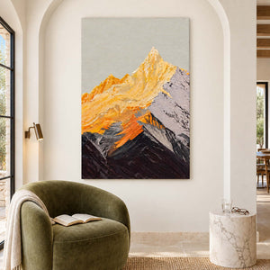 Frameless mountain artwork with golden peaks and dark ridges in an arched reading nook above a green chair.