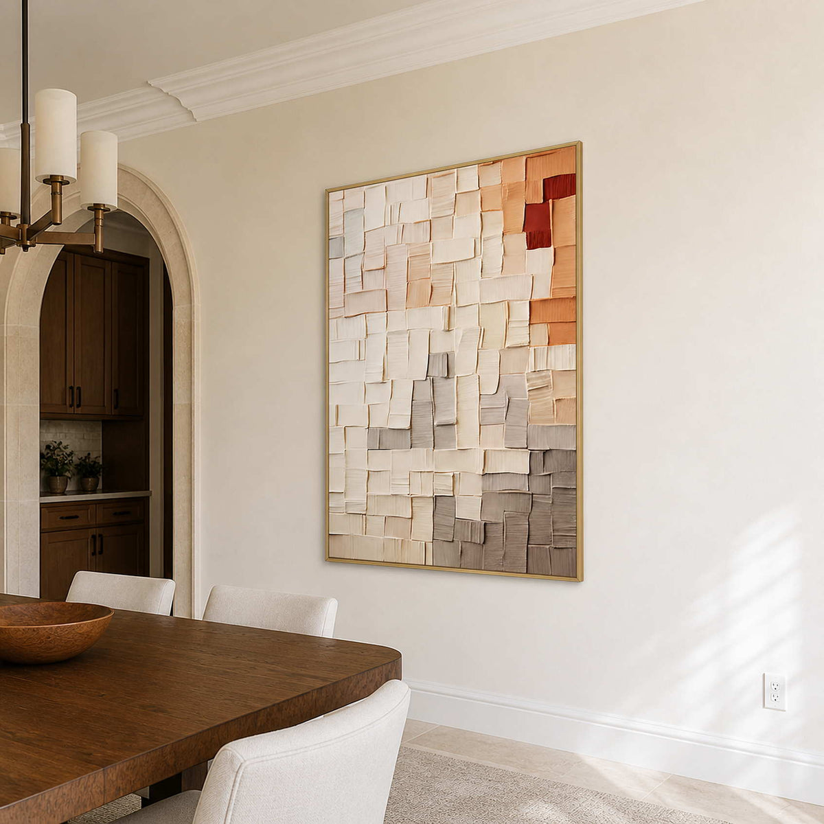 Gold-framed textured abstract wall art beside a wooden dining table and cream upholstered chairs.