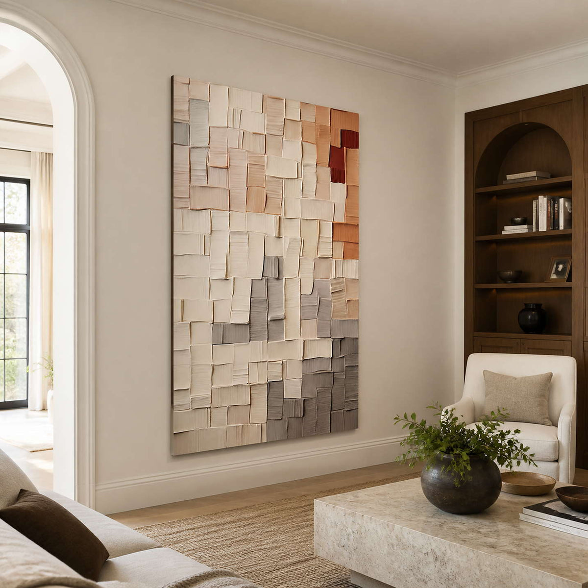 Frameless textured grid artwork beside bookshelves and cream seating in a warm living room.