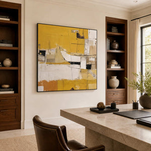 Black-framed yellow abstract artwork between dark wooden shelves beside a stone-topped home office desk.