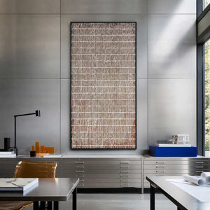 Black framed lattice artwork displayed beside architectural models in a design studio.