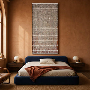 White framed narrow lattice painting above a blue upholstered bed.