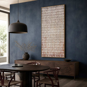 Wood framed brown and white grid painting beside a round dining table.