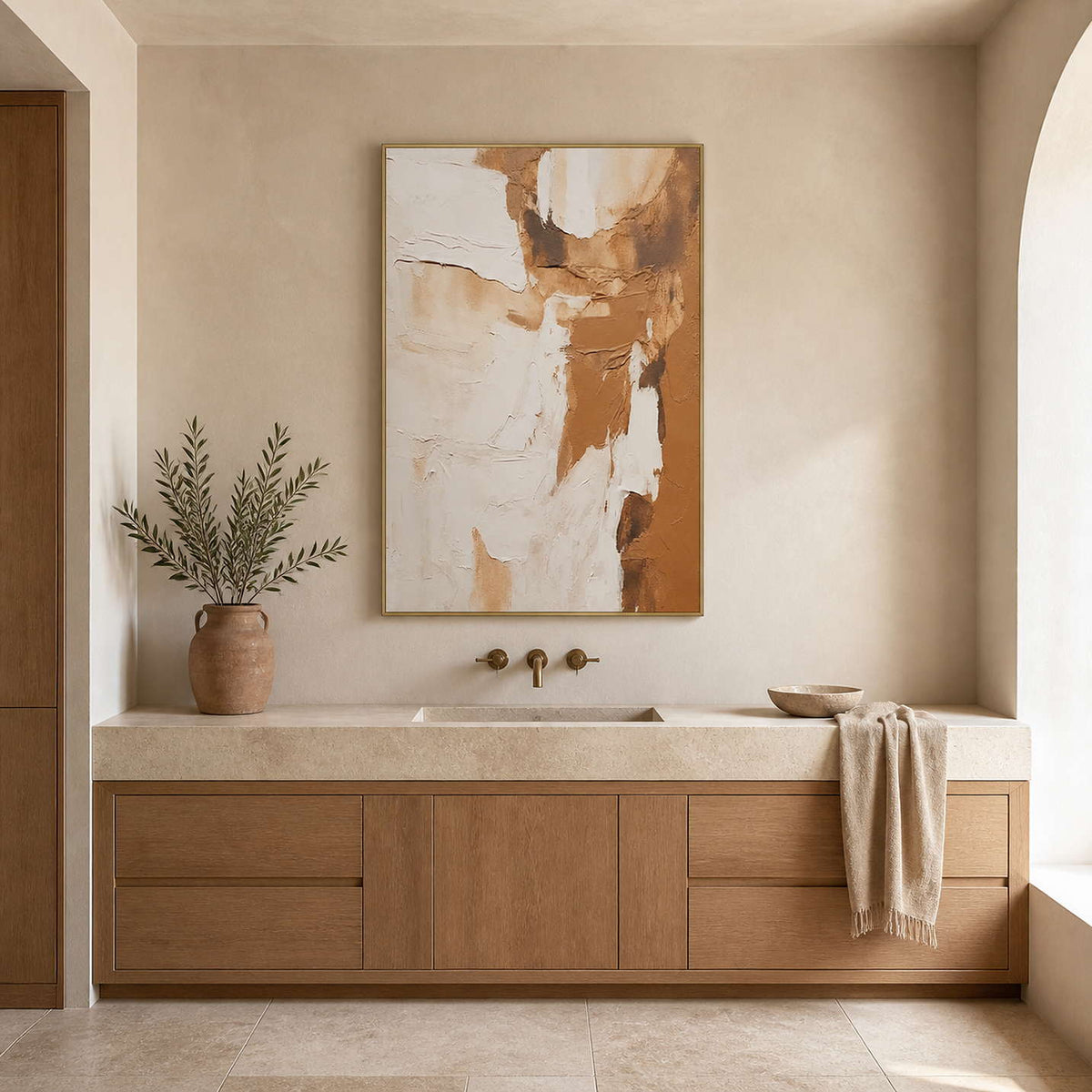 Gold framed warm abstract artwork above a stone vanity in a neutral bathroom.