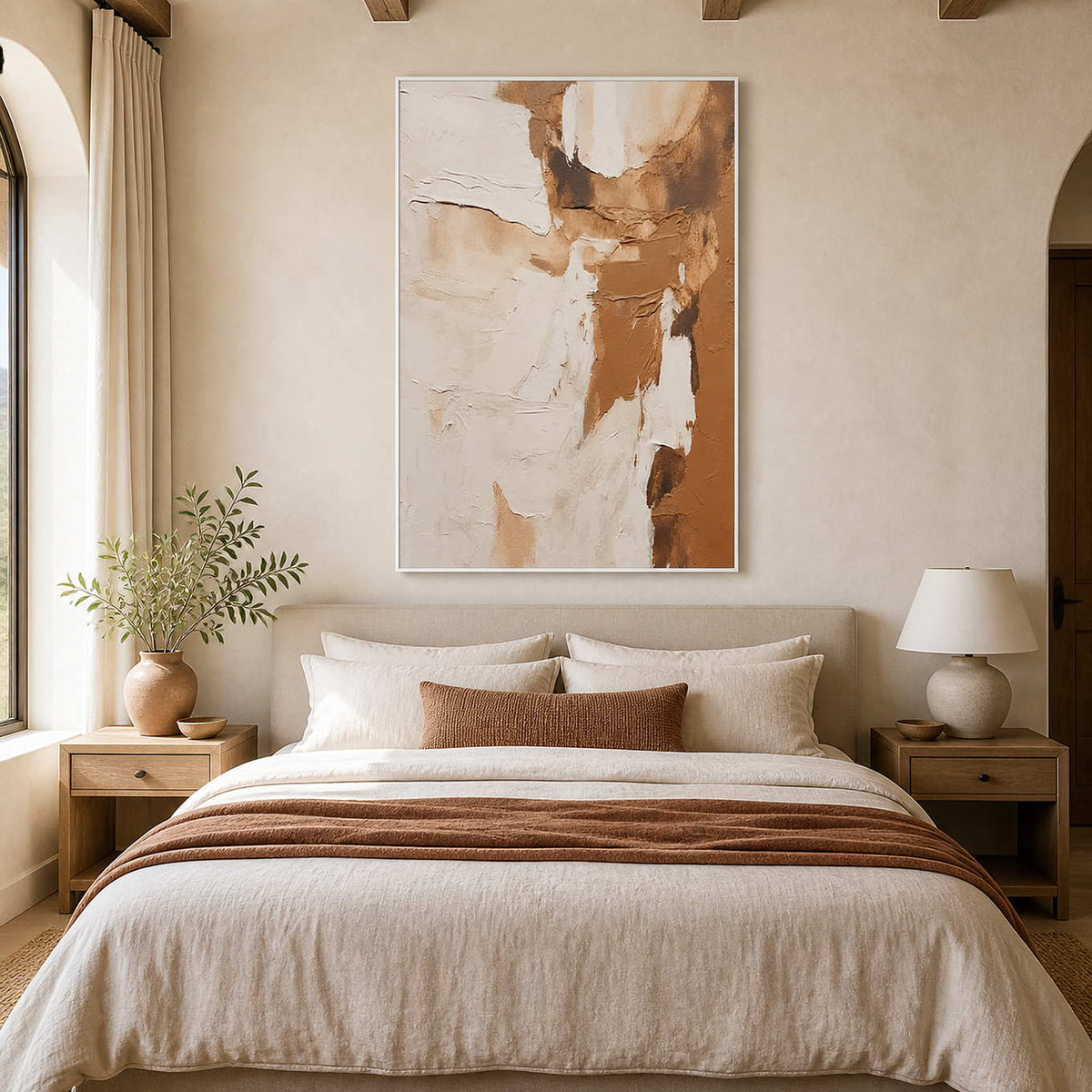White framed caramel and cream artwork above a bed with warm neutral linens.