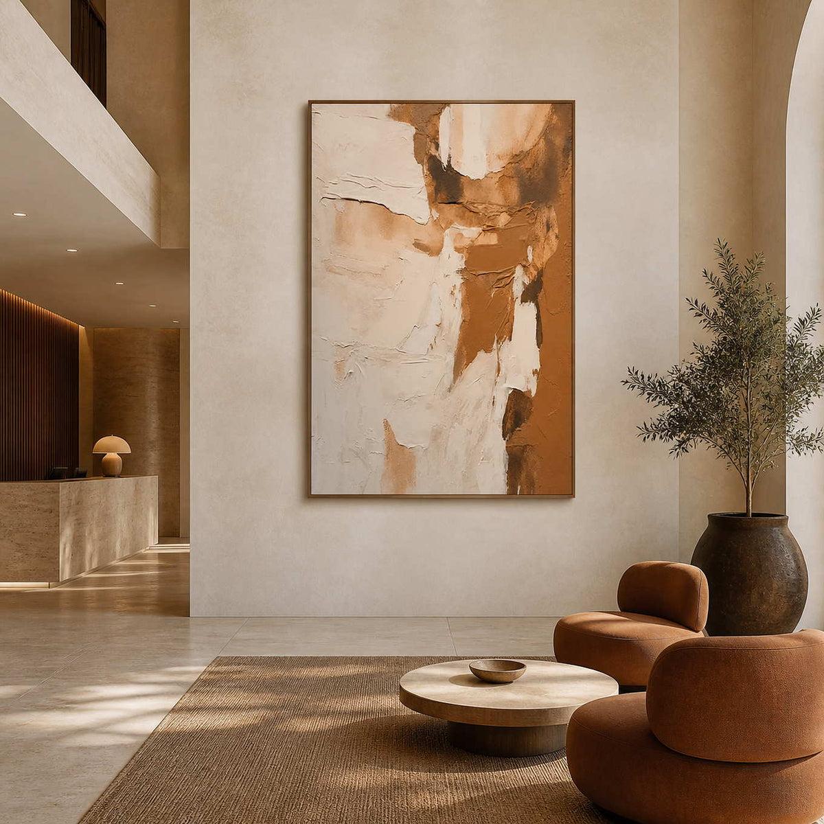 Wood framed cream and tan artwork above caramel lounge chairs in a hotel lobby.