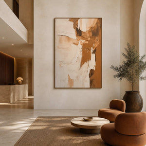 Wood framed cream and tan artwork above caramel lounge chairs in a hotel lobby.