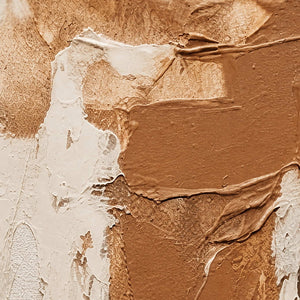 Close detail of raised cream edges and caramel strokes over a grainy surface.