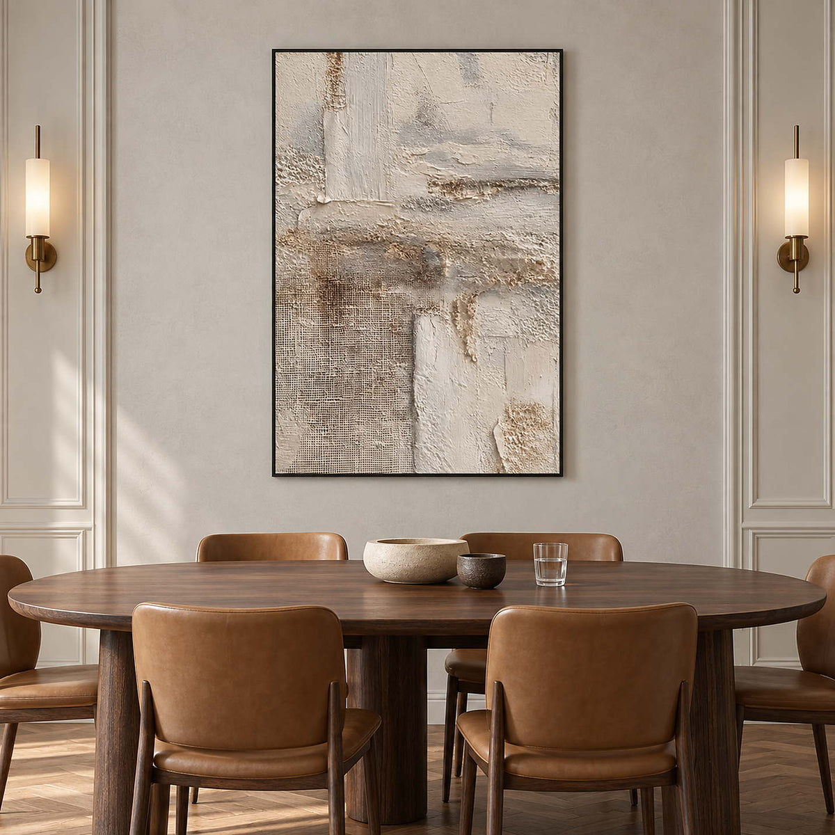 Cream and gray abstract over an oval dining table with brown chairs between wall sconces.