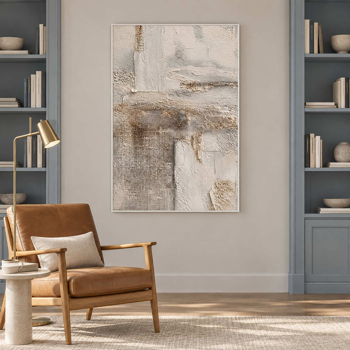 Cream texture artwork near a brown reading chair between blue-gray bookshelves.