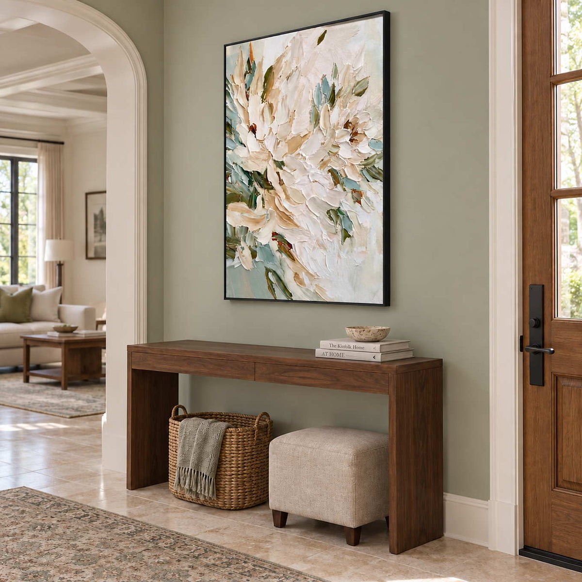 Tenderly in Bloom in a black frame above a wood entryway console with a woven basket and upholstered stool.