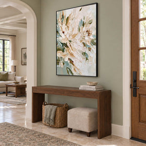 Tenderly in Bloom in a black frame above a wood entryway console with a woven basket and upholstered stool.