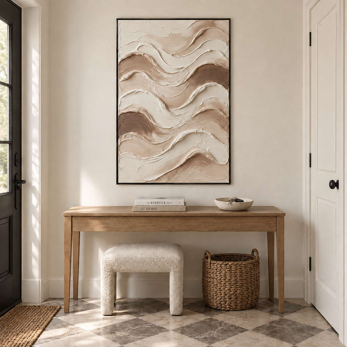 Tenderness in a black frame above a light wood hallway console with a cream stool and woven basket.