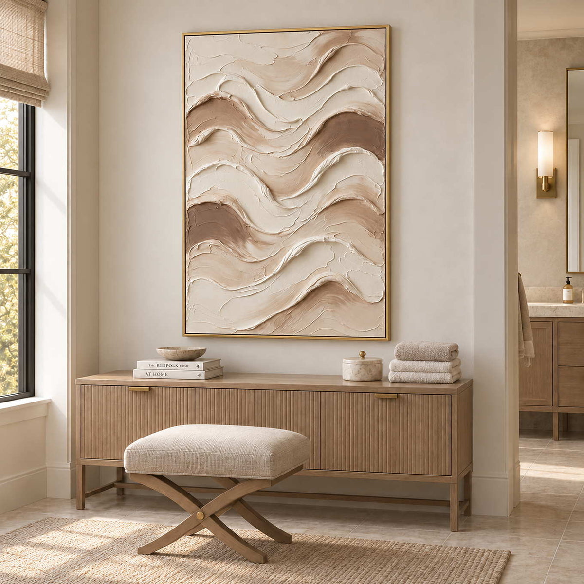 Tenderness in a gold frame above a fluted wood cabinet with towels beside a cushioned stool in a bathroom dry area.