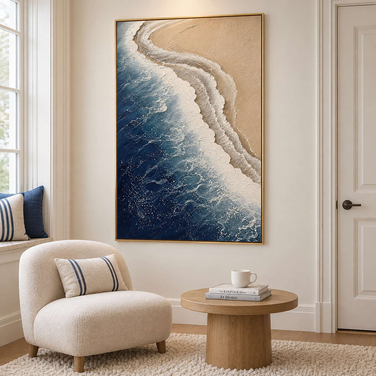 White surf curling along a sandy shore beside dark blue water in a gold frame, displayed beside seating in a lounge.