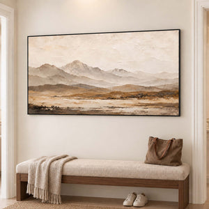 Soft taupe mountains above a muted ochre plain in a black frame, displayed in a hallway.