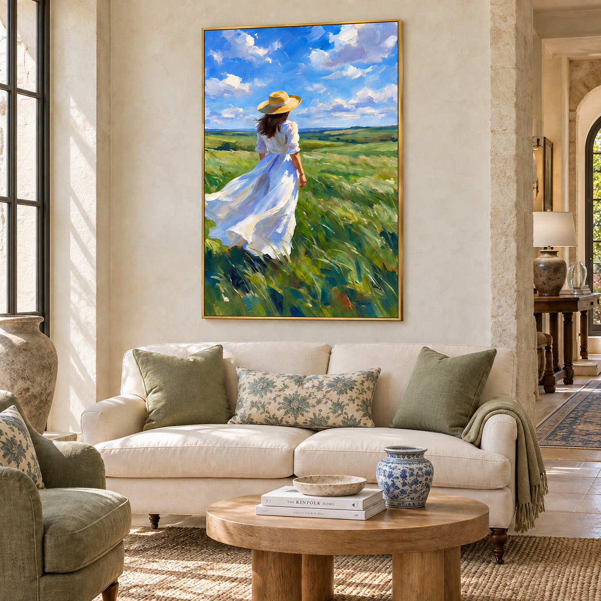 The Fields Await in a gold frame above a cream sofa with green cushions and an oval wood table in a lobby.