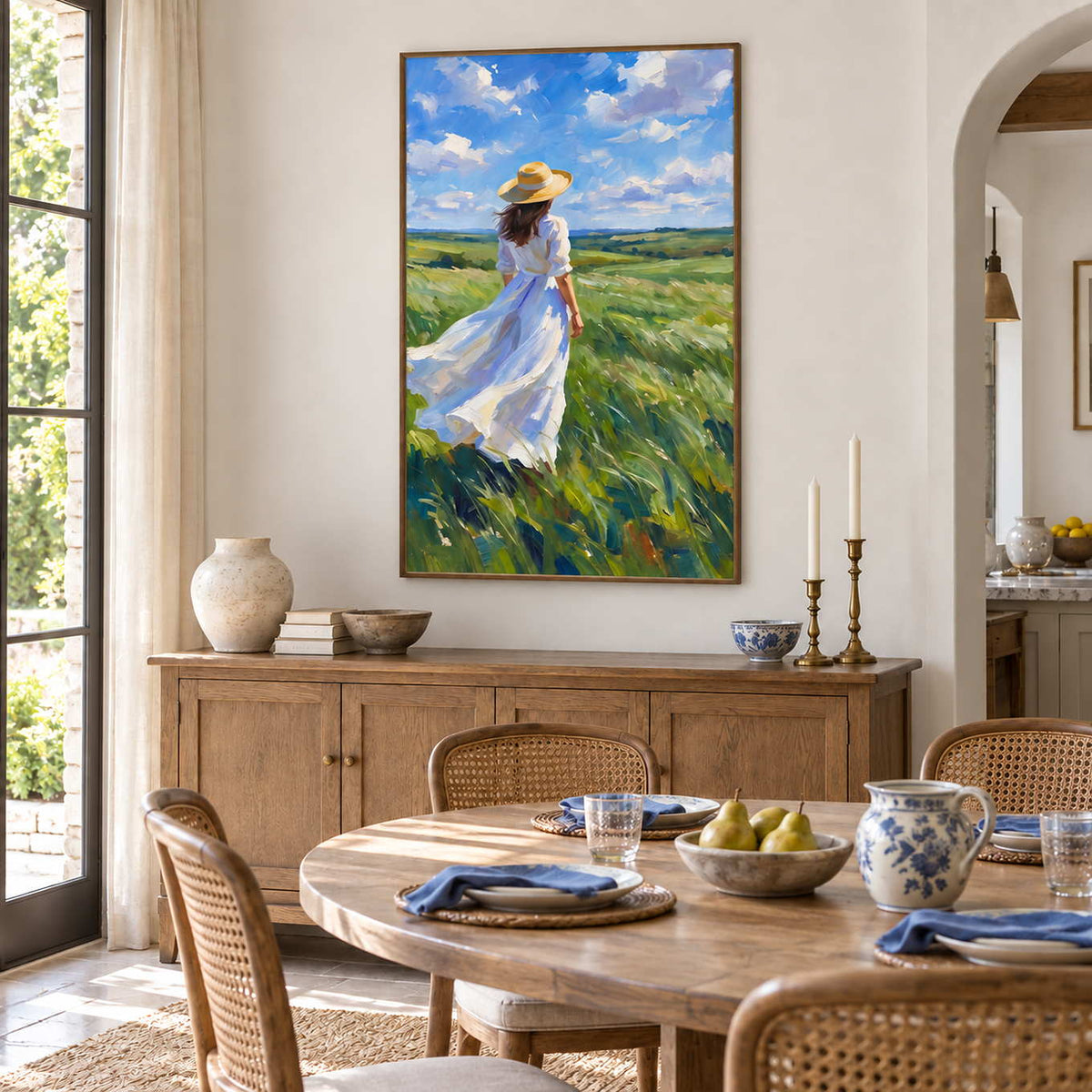 The Fields Await in a wood frame above a sideboard beside a round wood dining table and woven-back chairs.