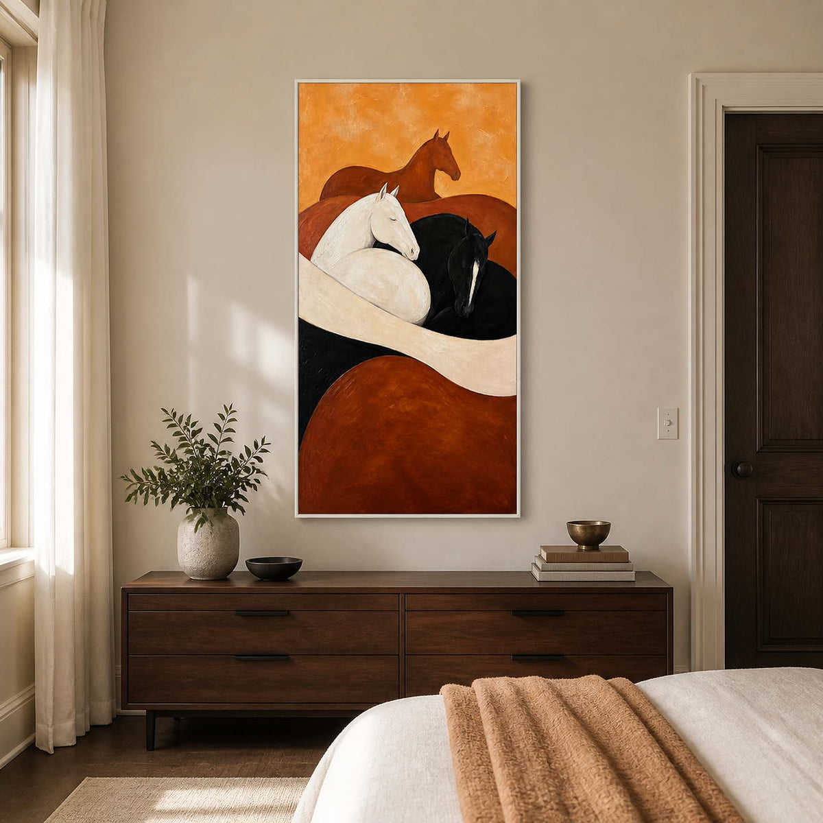 White framed equestrian artwork above a walnut dresser beside a softly dressed bed.
