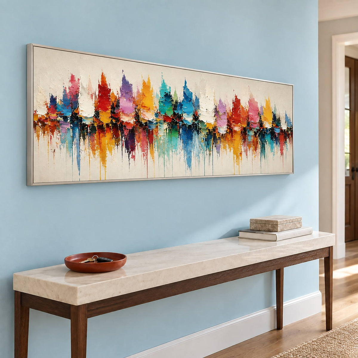 Panoramic harbor painting with colorful sail-like shapes and reflections in a silver frame in an entryway.