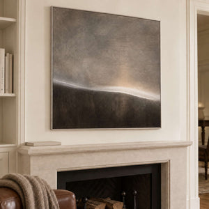 A thin glowing horizon between smoky gray and dark brown fields in a silver frame, displayed above a fireplace.