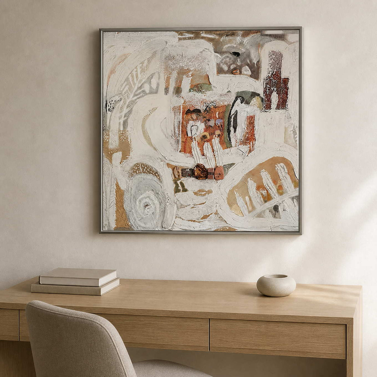 Silver framed cream and rust abstract artwork above a pale wooden home office desk.