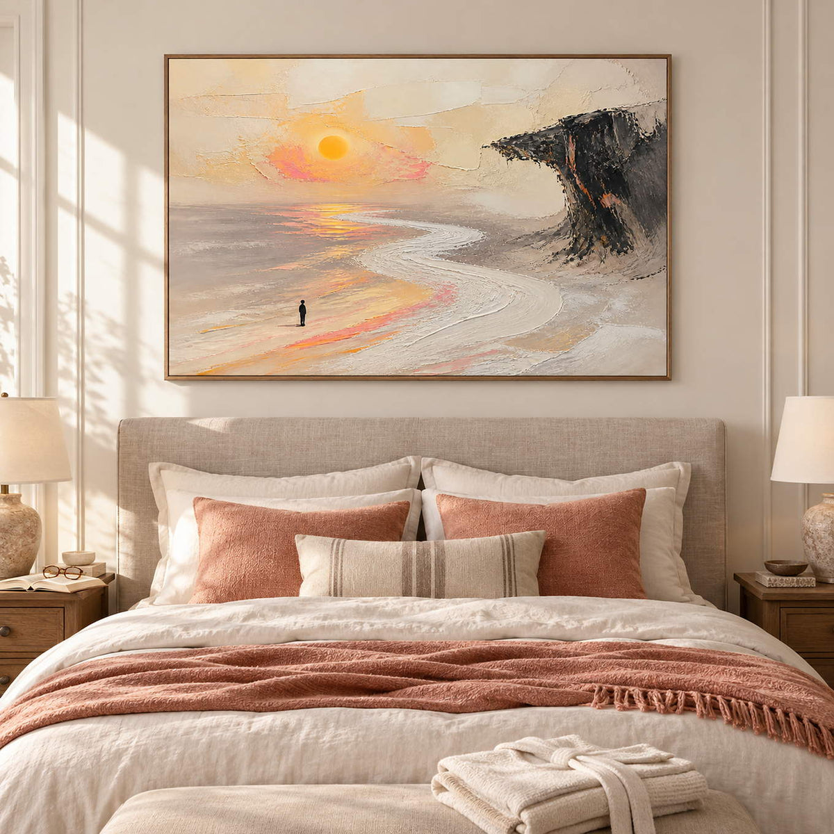 Landscape painting with a lone figure, amber sun, pale shore, and dark cliff in a brown wood frame in a bedroom.