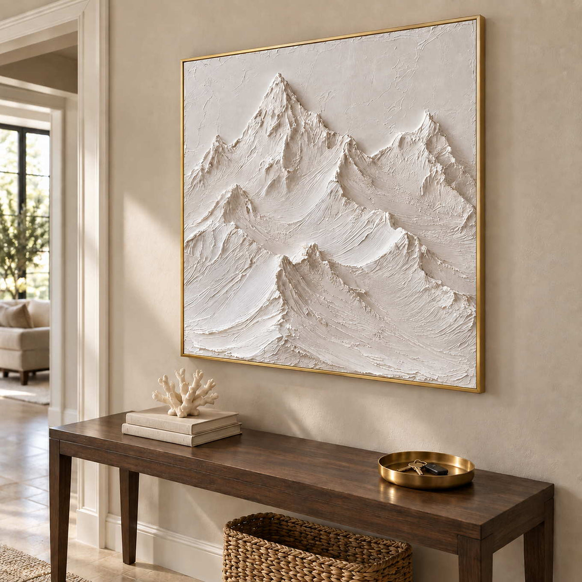 The Mountains Stand Watch in a gold frame above a dark wood console with pale coral decor and a brass bowl.