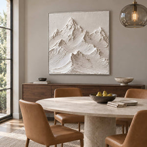 The Mountains Stand Watch in a silver frame above a wood sideboard beside a round stone table and tan chairs.