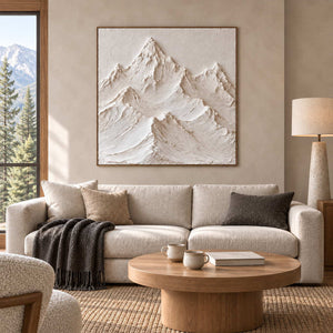 The Mountains Stand Watch in a wood frame above a cream sofa with charcoal cushions and a round wood table.