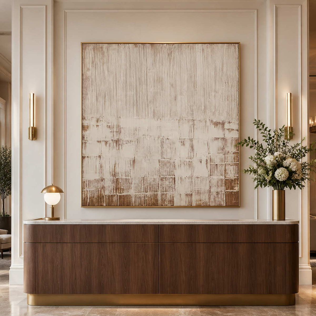 Gold framed cream and brown abstract artwork above a curved hotel lobby console.